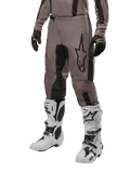 Alpinestars 2024 Fluid Lurv Hose, Motocross-Hose, Mud Black und Schwarz, mit Alpinestars-Logo, getragen mit schwarzen Handschuhen und weißen Motocross-Stiefeln, sportliches Design für Offroad-Rennsport