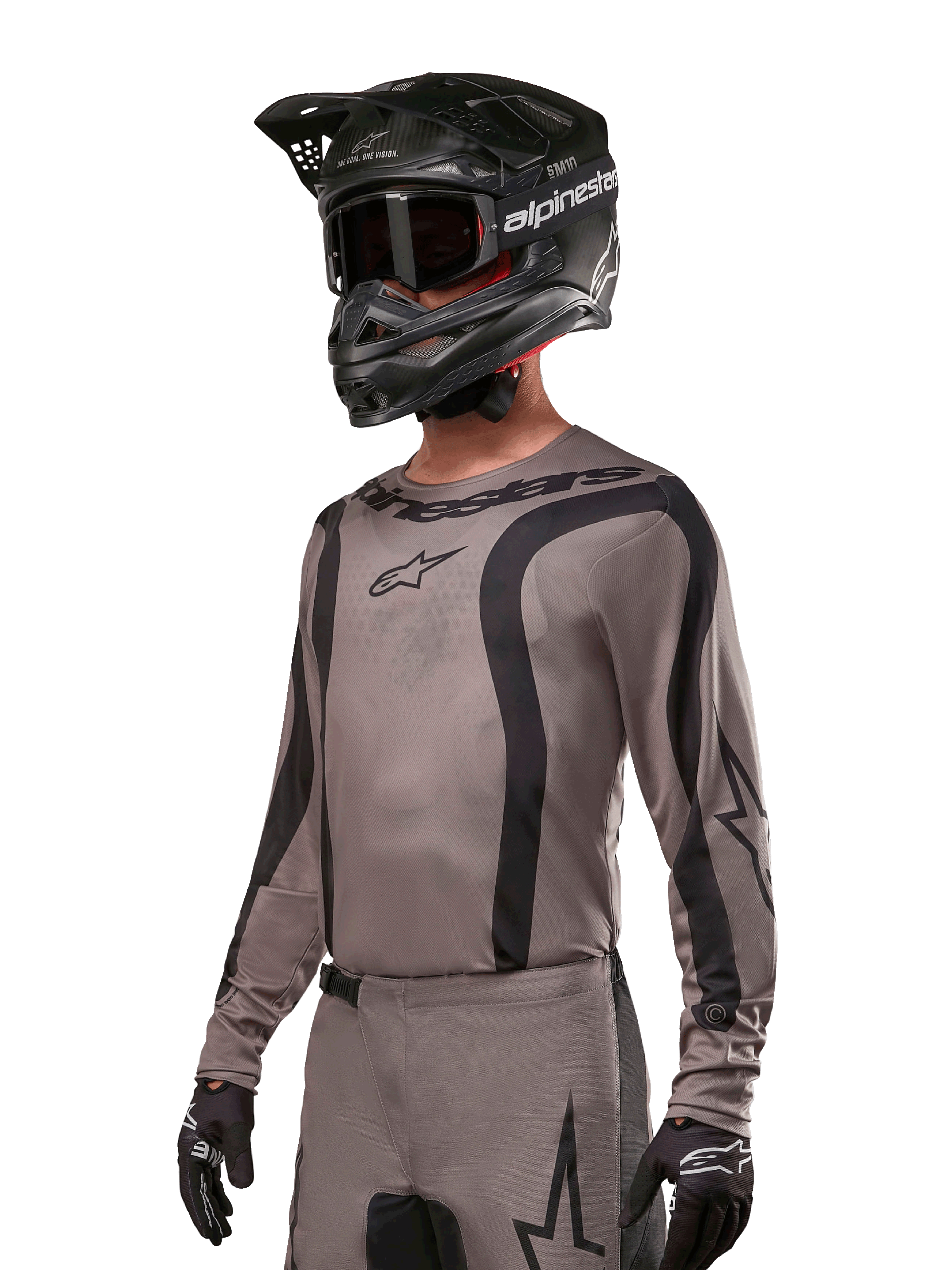 Alpinestars 2024 Fluid Lurv Trikot, Motocross-Jersey, Mud Black und Grau, langärmliges Design mit geschwungenen schwarzen Streifen und Logos, getragen mit passender Hose und einem schwarzen Motocross-Helm, abgestimmte Offroad-Rennausrüstung