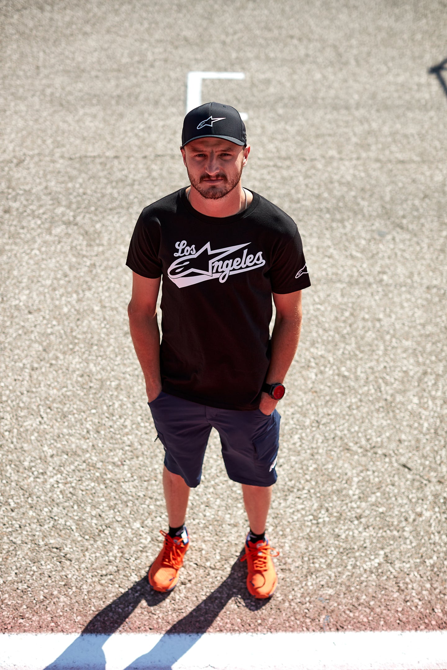 Jack Miller wearing a black t-shirt with 'Los Angeles' and a cap with Alpinestars logo on a textured wall background