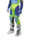 Alpinestars 2024 Racer Hoen Hose, Motocross-Hose, Neongelb und Nachtblau, mit roten Sternlogos und schwarzen Knie-Innenpaneelen, getragen mit passendem Trikot und weißen Motocross-Stiefeln, Performance-Ausrüstung für Offroad-Rennsport