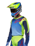 Alpinestars 2024 Racer Hoen Jersey, Motocross-Trikot, Gelb Fluo und Blue Night Navy mit roten Logos, getragen mit einem dazu passenden gelben, blauen und roten Helm und blauen Handschuhen, lebhafte Ausrüstung für Offroad-Rennen