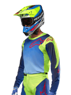 Alpinestars 2024 Racer Hoen Jersey, Motocross-Trikot, Gelb Fluo und Blue Night Navy mit roten Logos, getragen mit einem dazu passenden gelben, blauen und roten Helm und blauen Handschuhen, lebhafte Ausrüstung für Offroad-Rennen