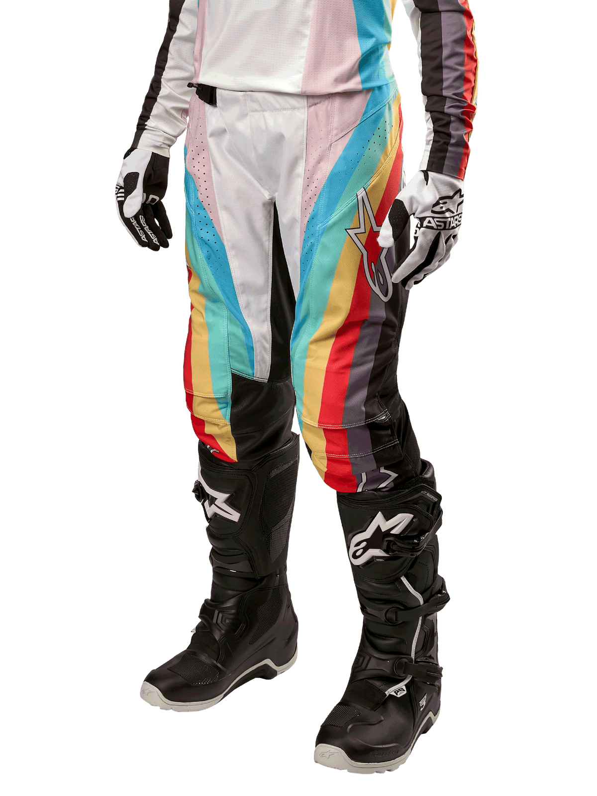 Alpinestars Stella 2024 Techstar Damenhose, Motocross-Hose, Schwarz-Mehrfarbig mit diagonalen roten, gelben und blauen Streifen, getragen mit schwarzen Stiefeln und weißen Handschuhen, mit schützenden schwarzen Knieeinsätzen und markantem Branding für Offroad-Rennen.