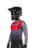 Alpinestars 2024 Supertech Dade Trikot, Motocross-Jersey, Iron Red Berry und Grau, langärmlig mit lasergeschnittenen Perforationen, getragen von einem Fahrer mit schwarzem Helm und Handschuhen, athletische Profi-Rennpassform