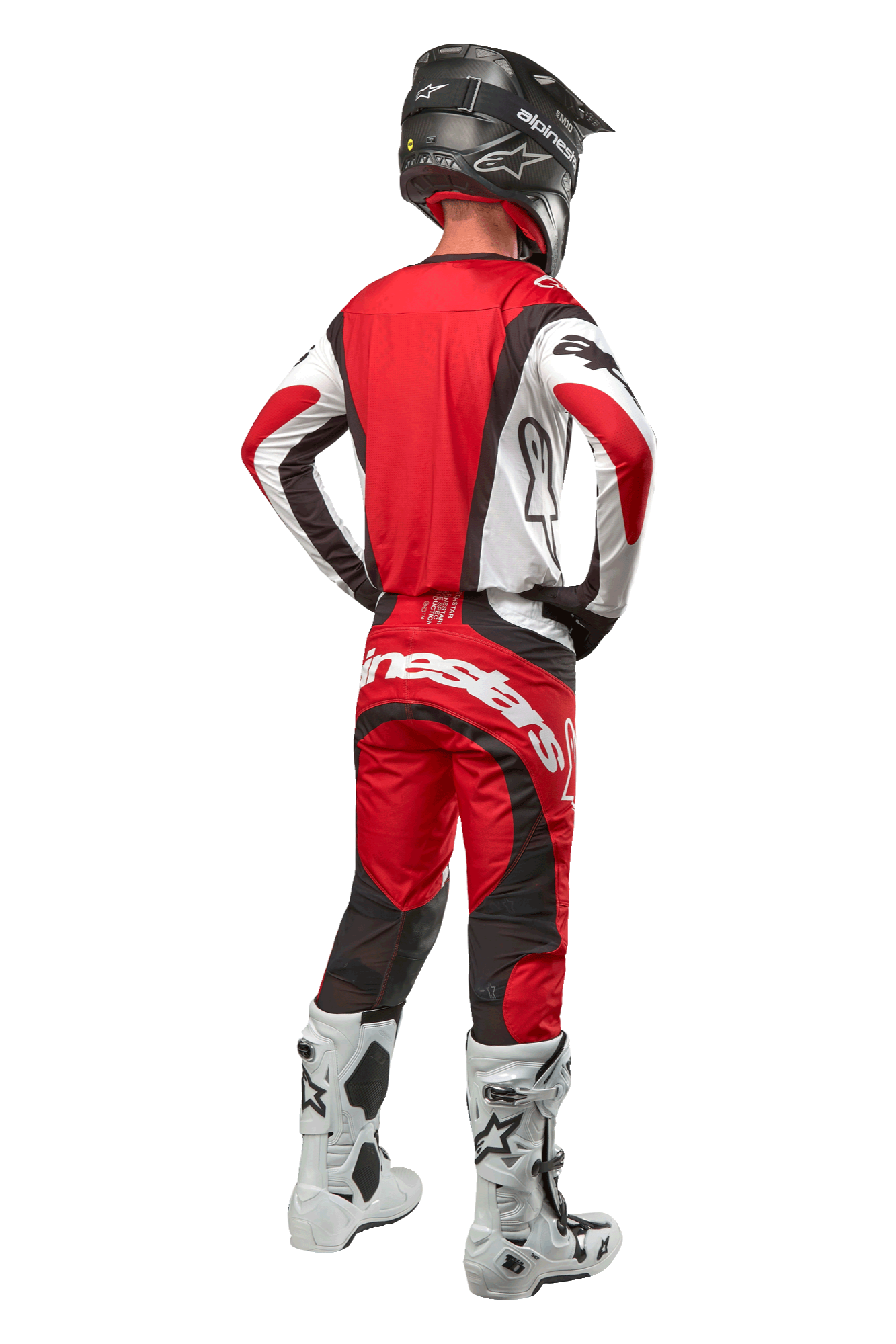 Alpinestars 2024 Techstar Ocuri Hose, Motocross-Hose, Mars Rot Weiß Schwarz, Rückansicht eines Motocross-Fahrers in kompletter Rennausrüstung, einschließlich passendem Jersey, schwarzem Helm und weiß-schwarzen Stiefeln, hebt das Alpinestars-Branding und die strapazierfähige Stoffkonstruktion hervor.