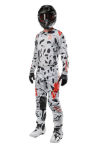 Alpinestars 2024 Techstar Rantera Hose, Motocross-Hose, Haze Gray Camo, getragen mit passendem Jersey, schwarzem Helm und weiß-schwarzen Stiefeln, mit schwarzen abstrakten Mustern und roten Akzenten, komplette Offroad-Rennausrüstung