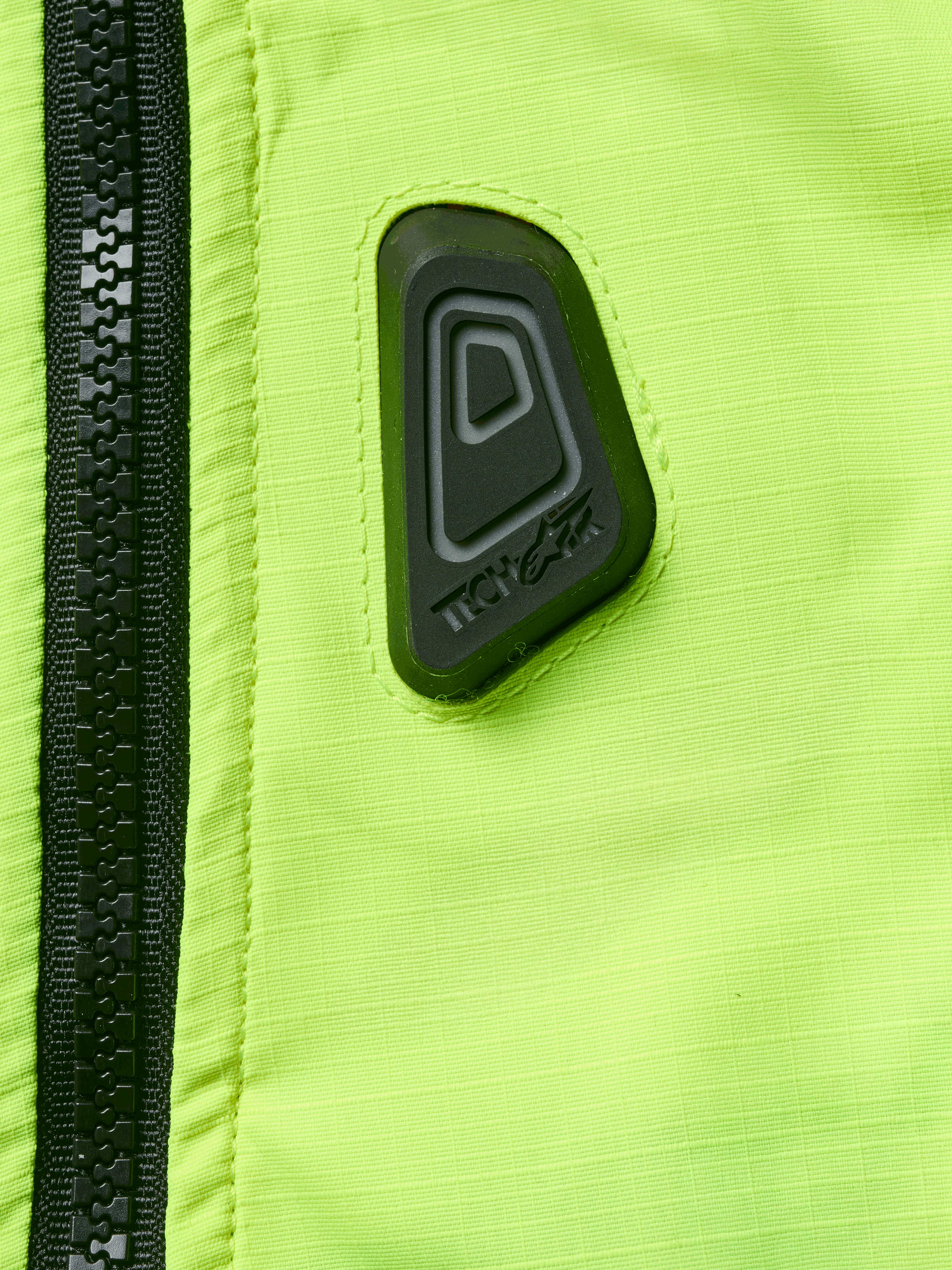 Alpinestars Tech-Air® 3 V2 System, Motorrad-Airbag-Weste, Nahaufnahme von wasserabweisendem Material in Gelb Fluo mit schwarzem Reißverschluss, schwarzer gummierter Tech-Air Logo-Patch, hochsichtbare Sicherheitsausrüstung