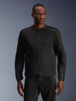 Männliches Model trägt die Alpinestars C-1 Air Jacke in Schwarz, moderne Motorradjacke mit großflächigen Tech-Mesh-Einsätzen und durchgehendem Frontreißverschluss, kombiniert mit passender schwarzer Motorradhose, urbane Lifestyle- und Pendler-Ästhetik
