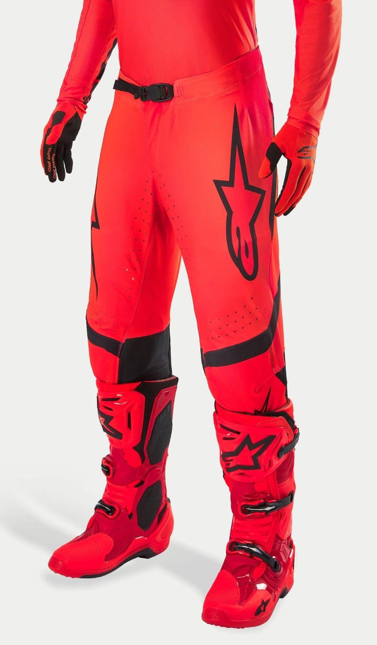 Alpinestars Supertech Ember LE Motocross-Hose, Red Fluo und Bright Red mit schwarzen Akzenten, getragen mit passenden roten Rennstiefeln und Handschuhen, markantes schwarzes Stern-Logo auf dem Bein, sichere Taillenschnalle, perforierte Zonen für Belüftung